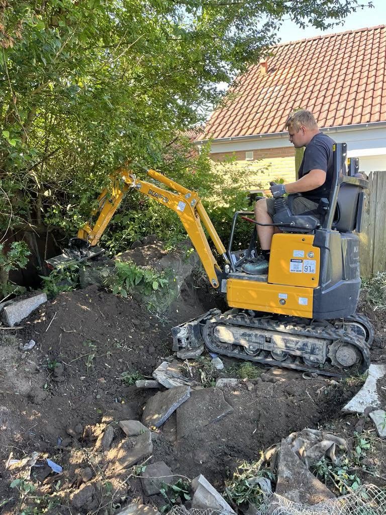Minigraver i arbejde med udgravning i have